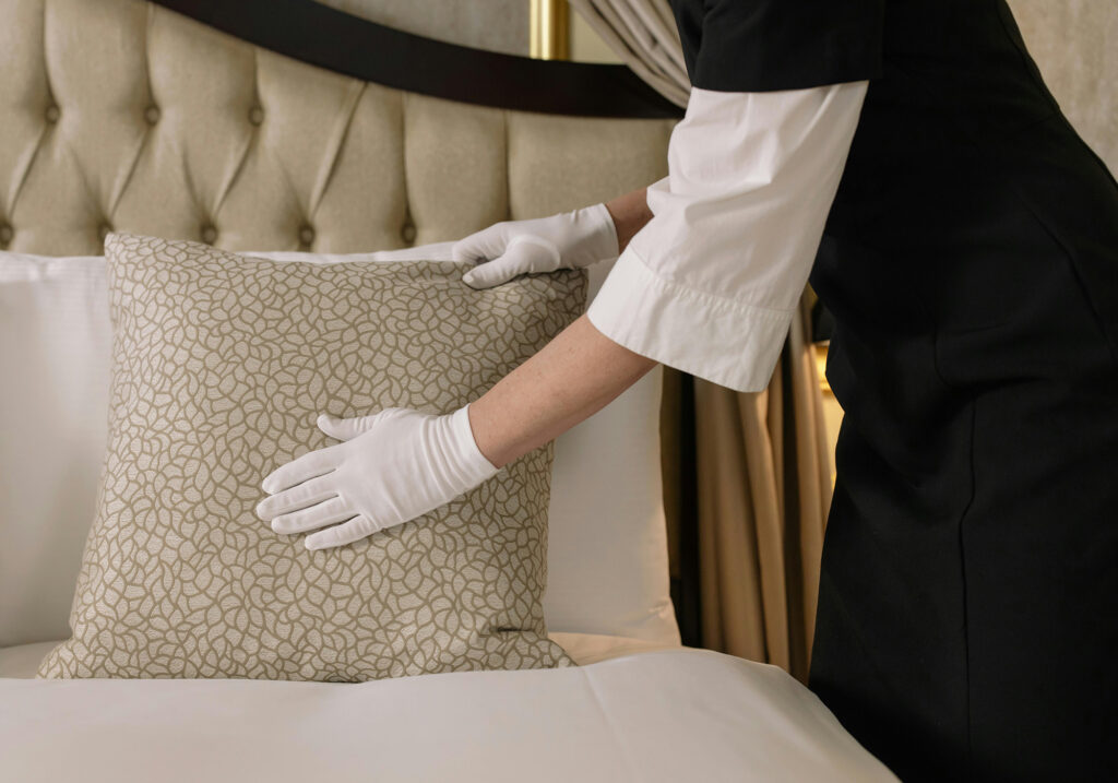 Hände in weißen Handschuhen beim Aufschütteln eines Kissens